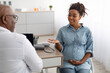 © Prostock-studio - Male doctor consulting young smiling pregnant woman