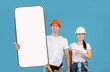 © Prostock-studio - Two Construction Workers In Helmet Holding Showing Big Cellphone Screen