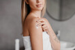 © Prostock-studio - Closeup of young lady applying moisturizing body lotion on shoulder, making beauty treatments in bathroom, crop