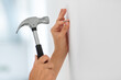 home improvement, repair and people concept - close up of hands hammering nail to wall