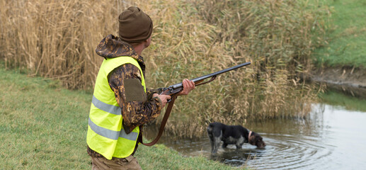 Wall Mural - Hunter man in camouflage with a gun during the hunt in search of wild birds or game. Autumn hunting season.