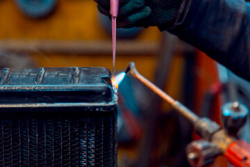 Canvas Print - Welder solders copper car radiator with gas torch