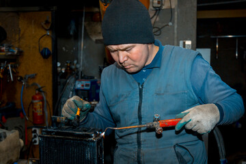 Sticker - Welder cleans a copper car radiator with a metal brush and a torch