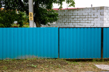 Close-up Of A Blue Metal Profile Fence. Corrugated Surface. Copy Space. Security. Private Property Fencing. Opaque Hedge. Outdoor House Exterior. Steel Material. High. Side View. Urban Or Indastrial