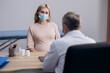 © Owl-vision-studio - Pregnant woman wearing medical mask talking to male doctor at hospital during pregnancy consultation. Expecting mother visiting gynecologist during coronavirus pandemic.