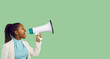 © Studio Romantic - Confident beautiful young black woman holding and yelling through megaphone. Loud activist girl makes important news announcement standing on blank green colour text copyspace studio banner background
