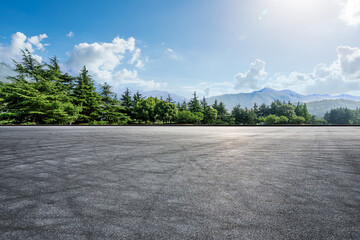 Wall Mural - Empty asphalt road and green forest with mountain scenery under blue sky