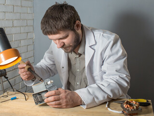 Wall Mural - a man soldering iron solders a part from an electrical appliance. the concept of repair of equipment.