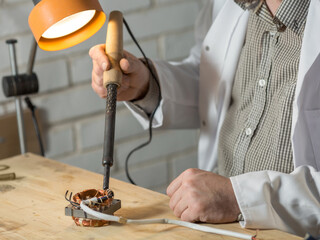 Wall Mural - a man soldering iron solders a part from an electrical appliance. the concept of repair of equipment