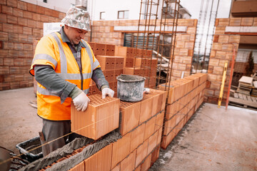 Wall Mural - Portrait of Construction worker bricklayer using bricks and mortar for building walls. industry details and construction equipment