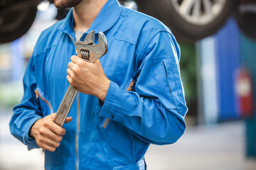 Wall Mural - Mechanic hand holding wrench equipment tool in auto repair garage. checking car damage broken, repairing vehicle business. motor technician maintenance after service