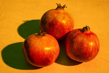 Three ripe pomegranates on the wooden table