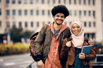 Wall Mural - Portrait of happy Muslim university couple outdoors and looking at camera.