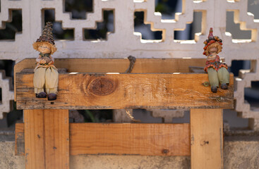 a couple of garden dolls sitting happily on a piece of wood