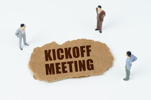 On A White Background, Figures Of Businessmen And Torn Cardboard With The Inscription - Kickoff Meeting