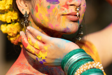 Wall Mural - Closeup of young beautiful girl woman lady in indian attire saree with dry organic color or colour or gulal or abeer or Holi powder on her face, Holi festival of color