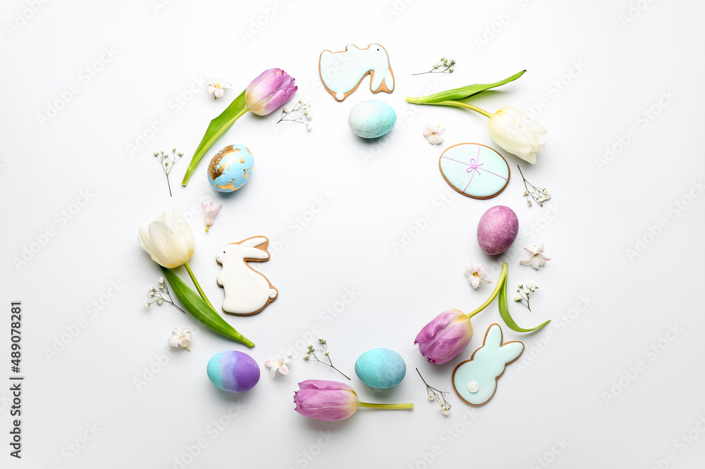 Stylish wreath with painted Easter eggs, cookies and flowers on white background