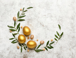 Wall Mural - Stylish wreath with golden Easter eggs and leaves on light background
