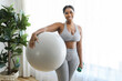 © Louis-Paul Photo - African american woman working out in home livingroom gym holding ball