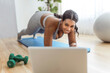 © Louis-Paul Photo - African american woman working out abdo in home livingroom gym with laptop