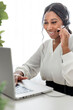 © Louis-Paul Photo - young African American businesswoman working at laptop at home office with headset