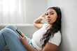 © Louis-Paul Photo - Attractive young African woman sitting on the couch at home with cellphone