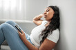 © Louis-Paul Photo - Attractive young African woman sitting on the couch at home with cellphone