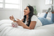 © Louis-Paul Photo - Happy Afro-American woman relaxing, eating popcorn while watching movie on bed