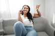 © Louis-Paul Photo - expresive young African woman sitting on the couch at home with cellphone
