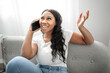 © Louis-Paul Photo - expresive young African woman sitting on the couch at home with cellphone