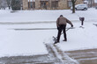 Old man bends over to shovel snow in midwest winter