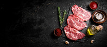Raw Pork Steak On A Stone Board With Tomato Sauce, Rosemary And Spices. On A Black Background. High Quality Photo