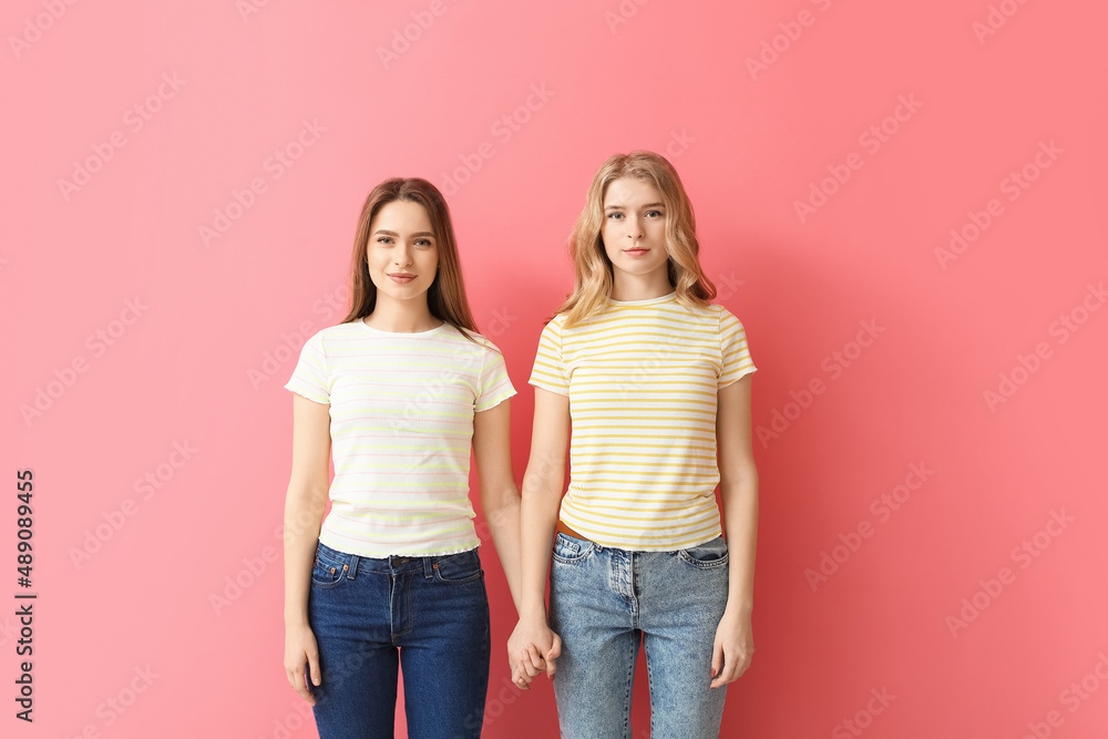 Portrait of young sisters on color background