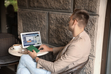 Poster - Handsome young man with passport booking tickets online at table in street cafe