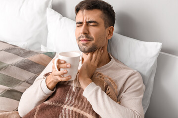 Sticker - Ill young man with sore throat drinking hot tea at home