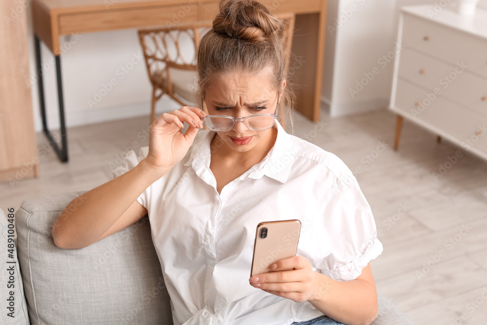 Stressed young woman using mobile phone at home