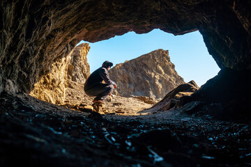 Wall Mural - A young tourist sitting in the Almanzora caves, Cala Peñon cut off a virgin and hidden beach in Almería. Mediterranean sea on the coast, Almería