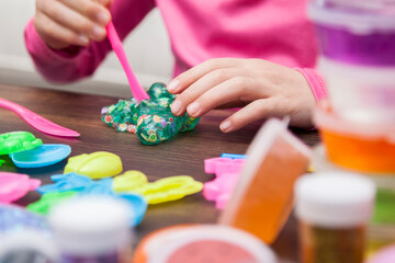 Young kids playing with colorful slime kit with glitter, toys, texture craft balls, and sparkles