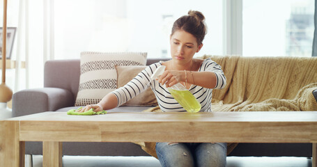 Sticker - I want this place to be spotless. Shot of a young woman cleaning the table in her living room.