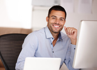 If you want the best then choose me. Portrait of a smiling young man sitting behind a computer screen.