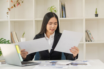 Asian businesswoman working on laptop analyzing financial graphs financial statistics profit growth business idea