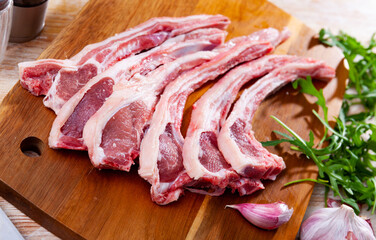 Wall Mural - Fresh raw young mutton chops on wooden cutting board with herbs and spices prepared for cooking on kitchen table. Healthy organic food