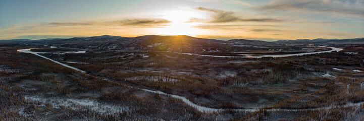 Amazing arctic sunrise over the Yukon Territory from aerial view in panoramic view over the snow, boreal forest below. 