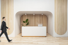 Man Walking In Modern Wooden Office Interior With Reception Desk. Waiting Area, Worker And Lobby Concept.