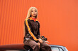 © Sergio Mena - Joven mujer afroamericana con cabello largo rubio y ropa deportiva sobre un fondo de color naranja
