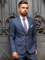 Wall Mural - A man in a business suit poses in front of an iron gate
