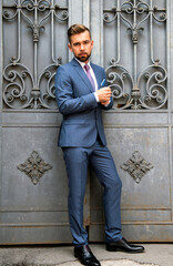 Wall Mural - A man in a business suit poses in front of an iron gate
