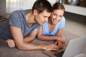 Poster - Getting all their info online. Shot of a happy young couple using a laptop on the floor together.