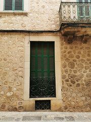 Canvas Print - A vertical of a green window under a balcony on an antique stone building in Mallorca, Spain