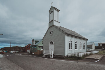 Sticker - A small wooden church with white walls and a grey roof in a gloomy weather